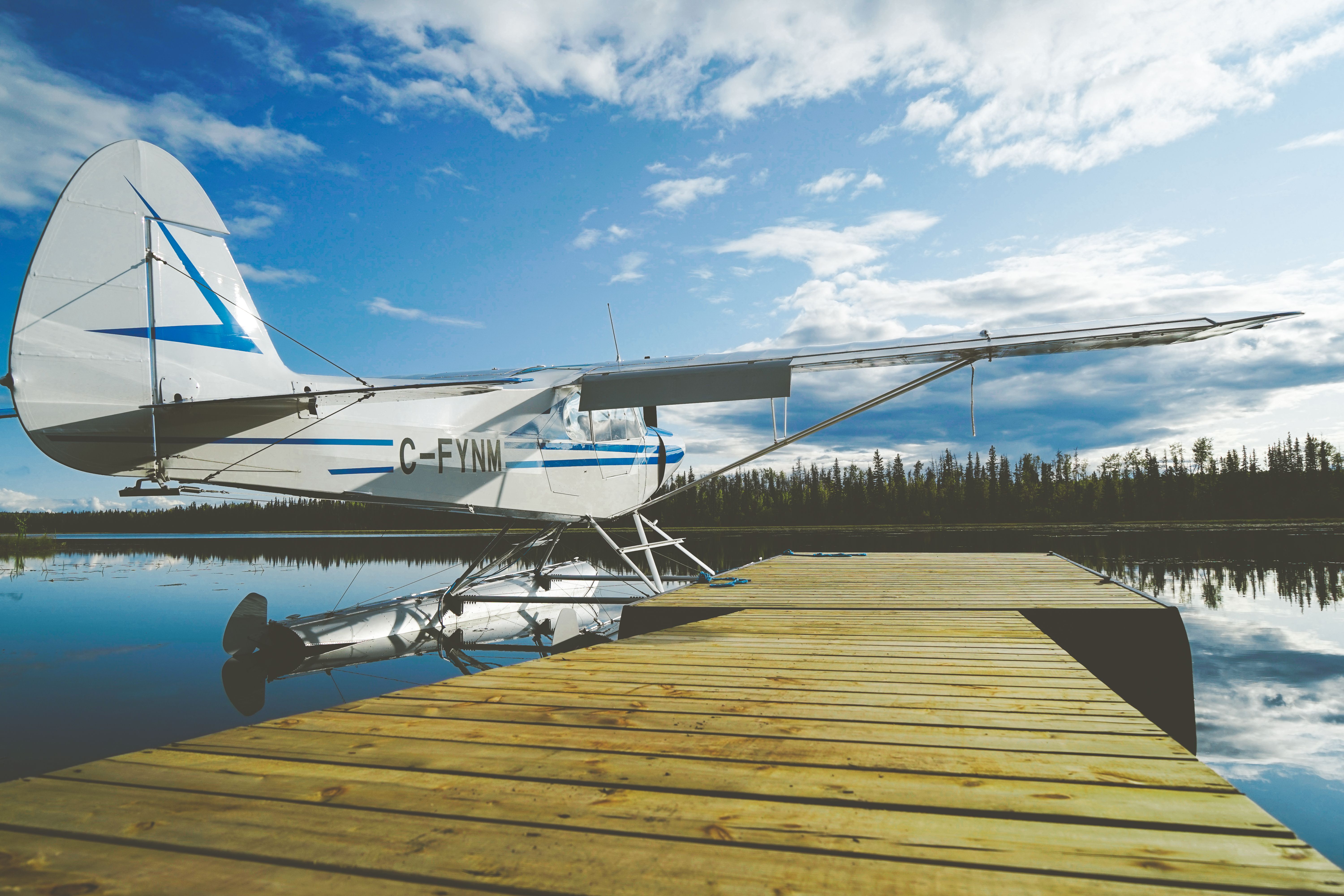 A floatplane resting on a calm lake under a bright sky