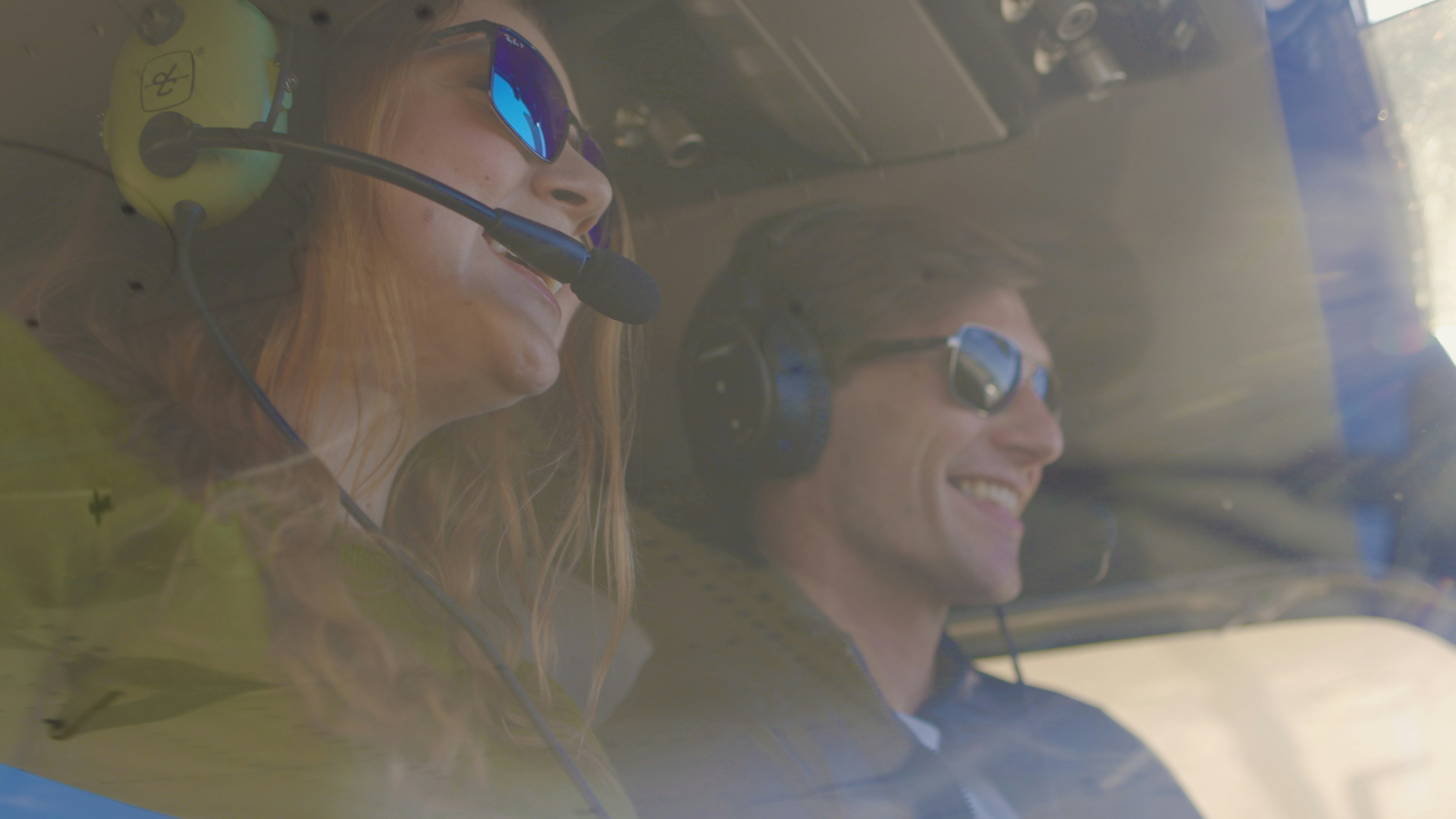 Two pilots smiling together in the cockpit of a small aircraft