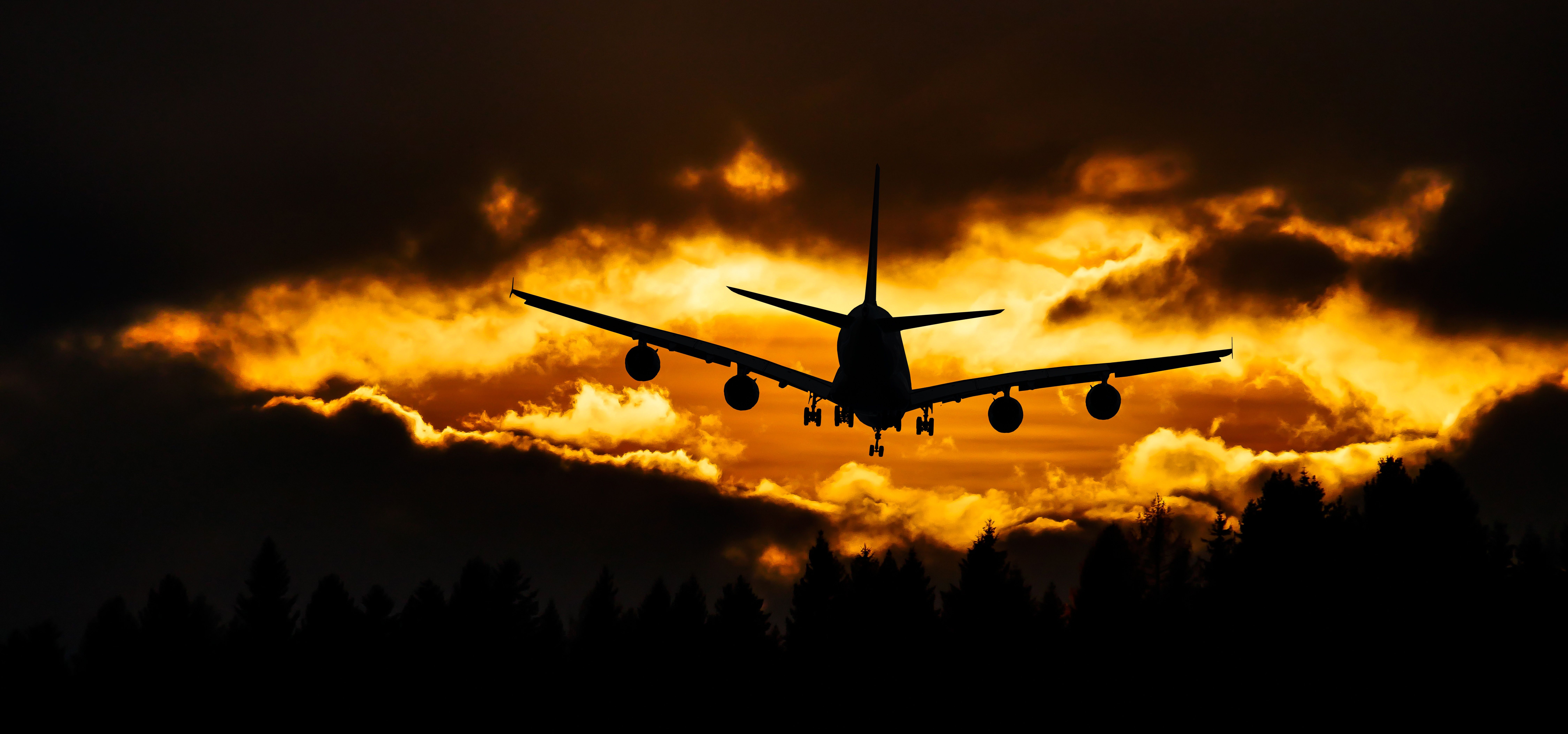 An airliner on approach silhouetted against a golden sunset