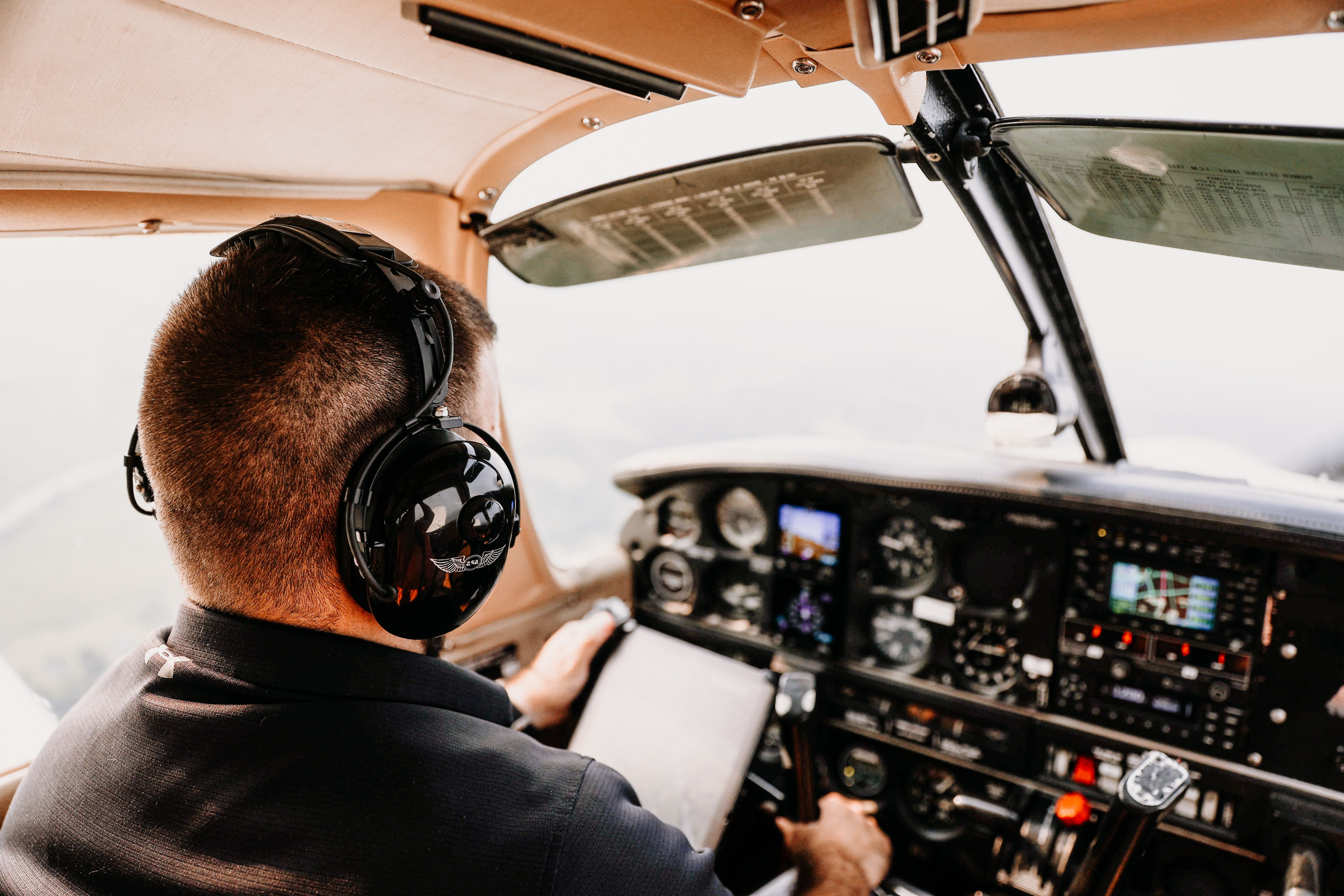 A pilot wearing a headset at the controls of a small aircraft